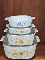 Four Corning Ware casserole dishes stacked and showing floral patterns and sizes