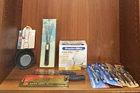 Full lot of kitchen accessories including basting pot with brush, hand mixer, knives, whisk, and nutcrackers.