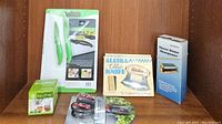 Lot arranged on shelf showing all items: cutting board with green paring knives, two Alaska souvenir knives, Easy Filter container, kitchen shears, and three stone sharpener box.