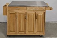 Front view of kitchen island cart showing stainless steel top, two top drawers and four paneled doors
