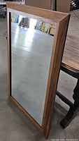 Front view of the mid century wood framed square mirror showing the frame edges and reflections