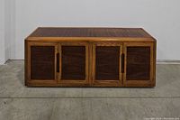 Front view of two-toned mid century sideboard with closed doors showing wood grain and recessed handles.