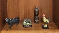 Group photo of four rustic animal figurines: bull, bird, fish eating decor, and rooster.