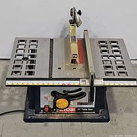 Front-facing view of the Ryobi 10-inch table saw showing the blade guard, work surface, and adjustment handles.