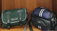 Two camera carrying cases, one green Sony branded and one black with white stripes
