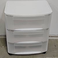 Front view of a white plastic storage cart with three transparent drawers and built-in handles.