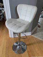 White adjustable bar stool chair with padded seat and backrest, chrome base, and footrest