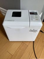 Full view of the white Sanyo bread maker with control panel and window on lid.
