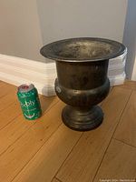 Full side view of large antique brass vase next to a soda can for size reference.