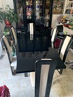 Top view of black rectangular dining table surrounded by six chairs, showing glossy table surface and chair upholstery.
