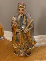 Front view of ceramic Chinese Star God figurine showing detailed traditional robe, facial features, and a child figure.