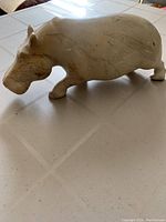 Side view of the off-white stone hippopotamus sculpture showing its smooth surface and natural veining.