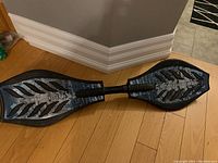 Top down view of the black Ripstik caster board showing textured deck with silver flame design and central torsion bar.