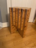 View of the wooden table from one side showing the interlocking block construction and natural wood grain.