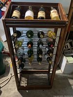 Front view of wooden wine rack holding various wine bottles in metal racks and on top shelf