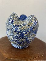 Tri-corner cobalt blue glass rose bowl with blue and white frit applied outside, showing starburst and dimpled pattern on a wooden stand.