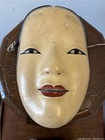 Front view of antique Japanese Ko-Omote Kagura mask showing oval face, cream color, red lips, and black eyes.