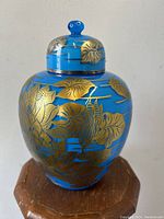 Front view of the antique blue glass temple jar with gold lily pad pattern and lid knob.