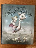 Front cover of the hardcover art book 'Beautiful Nightmares' by Nicoletta Ceccoli, showing whimsical fantasy artwork of a girl riding a strange animal.