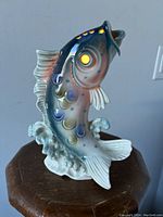Front view of porcelain leaping fish lamp showing detailed scale and fin painting and base wave design.