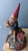 Side view of vintage Tom Clark gnome figurine showing detailed beard, red pointed hat, and pine cone in hands.