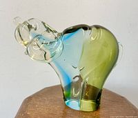 Side profile showing the green and blue glass body and clear glass head with abstract hound dog form.