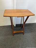 Front view of the teak fold-up table showing the rectangular top and foldable wooden legs.