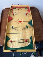 Top-down view of the wooden table hockey game showing player figures, goals, and markings