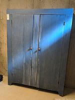 Front view of the blue wash solid wood pantry cabinet with two doors closed.