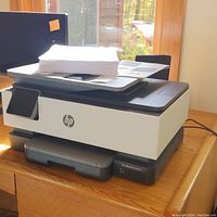 Side view of HP OfficeJet Pro 8025 printer with paper on top