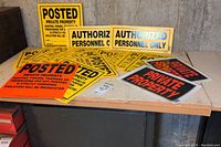 Photo showing multiple yellow and orange plastic property and warning signs spread on a table