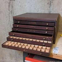 Front angle showing multiple drawers of the wooden tool chest with some drawers open revealing small compartments inside.