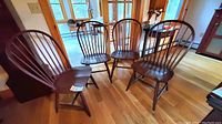 Four Windsor chairs grouped together on hardwood floor, showing overall condition and style.