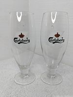 Two Carlsberg beer glasses side by side showing overall shape and logo placement