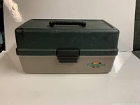 Closed Flambeau fishing tackle box showing two-tone green and gray plastic with black handle and clasp.