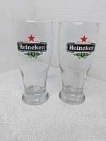Two clear glass Heineken beer glasses side by side