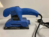 Side view of blue Mastercraft electric 1/3 sheet sander showing ergonomic handle, ventilation slots, power cord, and sanding base.