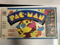 Top view of Pac-Man board game box showing colorful Pac-Man and ghost characters, and game title.