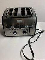 Front view of T-FAL Maison 4 slice toaster showing 4 slots, dual knobs, level levers and buttons, with power cord visible.