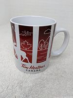 Front view of white ceramic coffee mug with red Tim Hortons Canada design featuring a moose and maple leaf graphic
