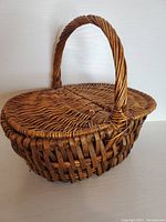 Closed wicker picnic basket showing woven handle and dual hinged lid.