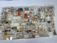 Overview photo showing many clear plastic cases containing various seashells of different sizes and shapes arranged on a white surface.
