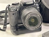 Close-up of Canon EOS Rebel XTi camera body with Canon 18-55mm zoom lens attached, showing camera front and lens details.