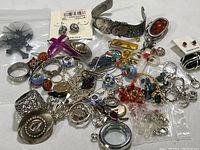 Full assortment of costume jewelry including earrings, bracelets, rings, pendants, and brooches spread on a surface