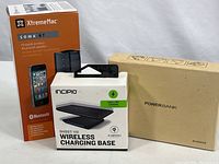 Three boxed electronic items: XtremeMac Soma BT wireless speaker in orange and black box, Incipio Ghost 110 wireless charging base in white box, and a brown box labeled PowerBank.