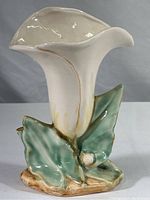 Side view of the McCoy calla lily vase showing white flower and green leaves base.