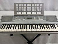 Front-facing full view of Yamaha YPT-300 electronic keyboard on stand with sheet music holder installed