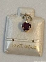 Close-up view of the yellow gold pendant with garnet gemstone on display holder showing '10 Kt Gold' mark.