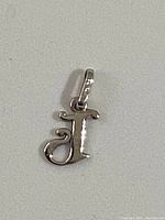 Photo of the 14K white gold pendant shaped as a 'j' on a white background.