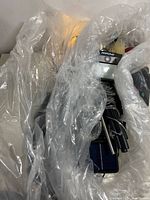 Lot contains multiple solar-powered garden lighting stakes, string lights, and accessories all wrapped in plastic.